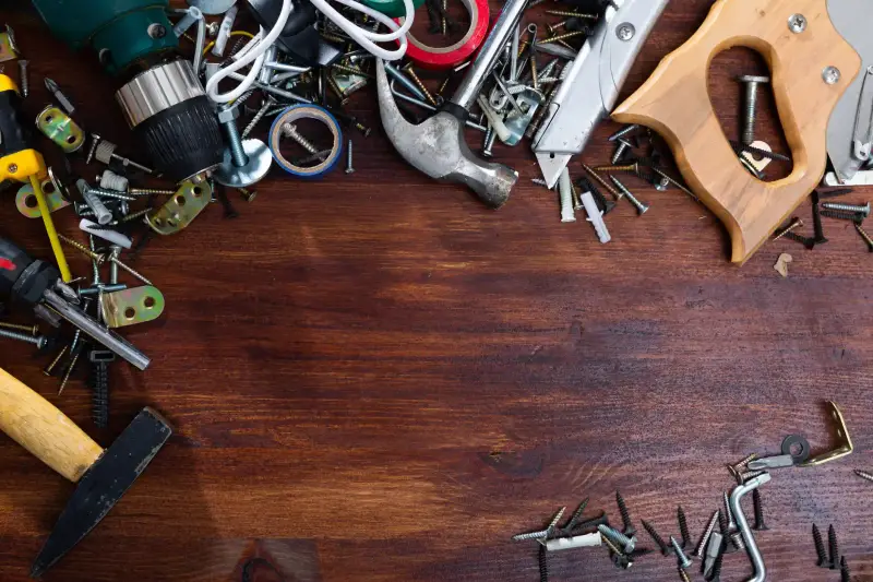 Hand tools, nails, and screws on a wooden table.