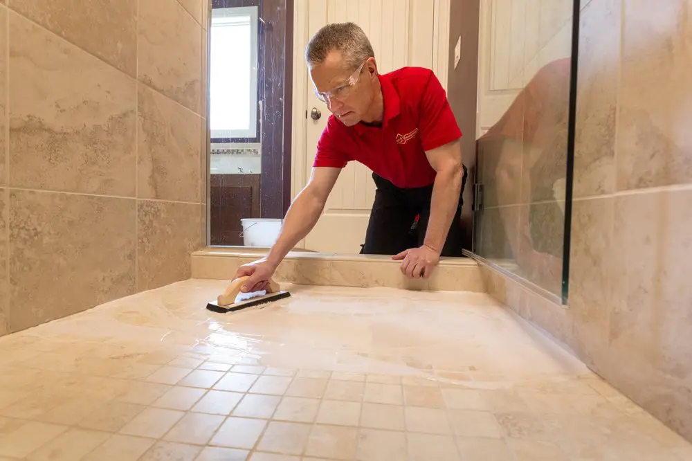 A handyman sealing a shower floor after completing new shower tile installation in Knoxville, TN.