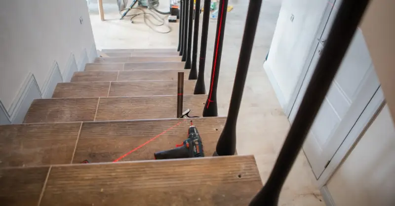 A basement staircase with tools lying on the steps and markings left by a handyman for stair repairs in McKinney, TX.