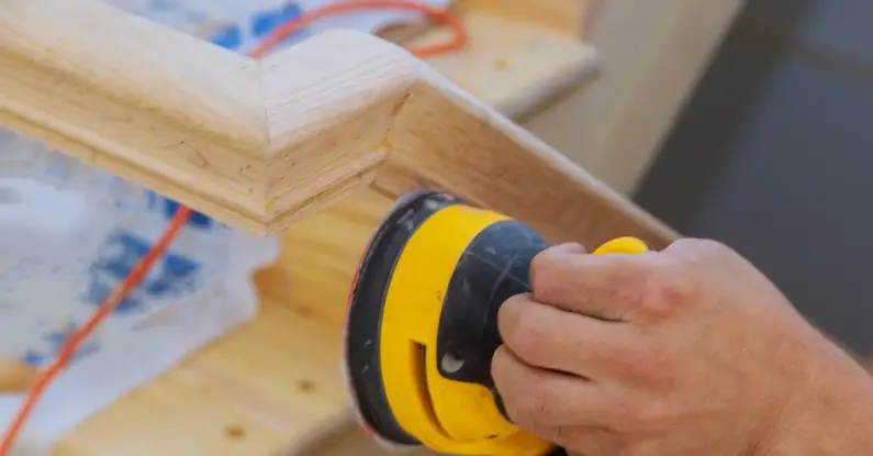 A powered sander being used on the railing of a staircase during an appointment for stair repair in Denton, TX.