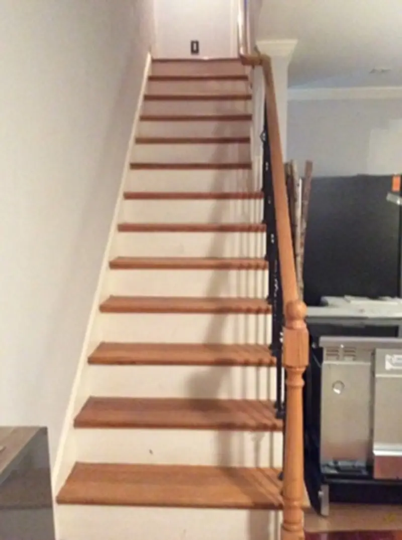  An interior staircase with white risers and brown treads on top, creating a contrasting color that helps improve accessibility for those with reduced depth perception or vision challenges that make it difficult to age in place.