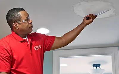 A Mr. Handyman tech repairing some ceiling drywall