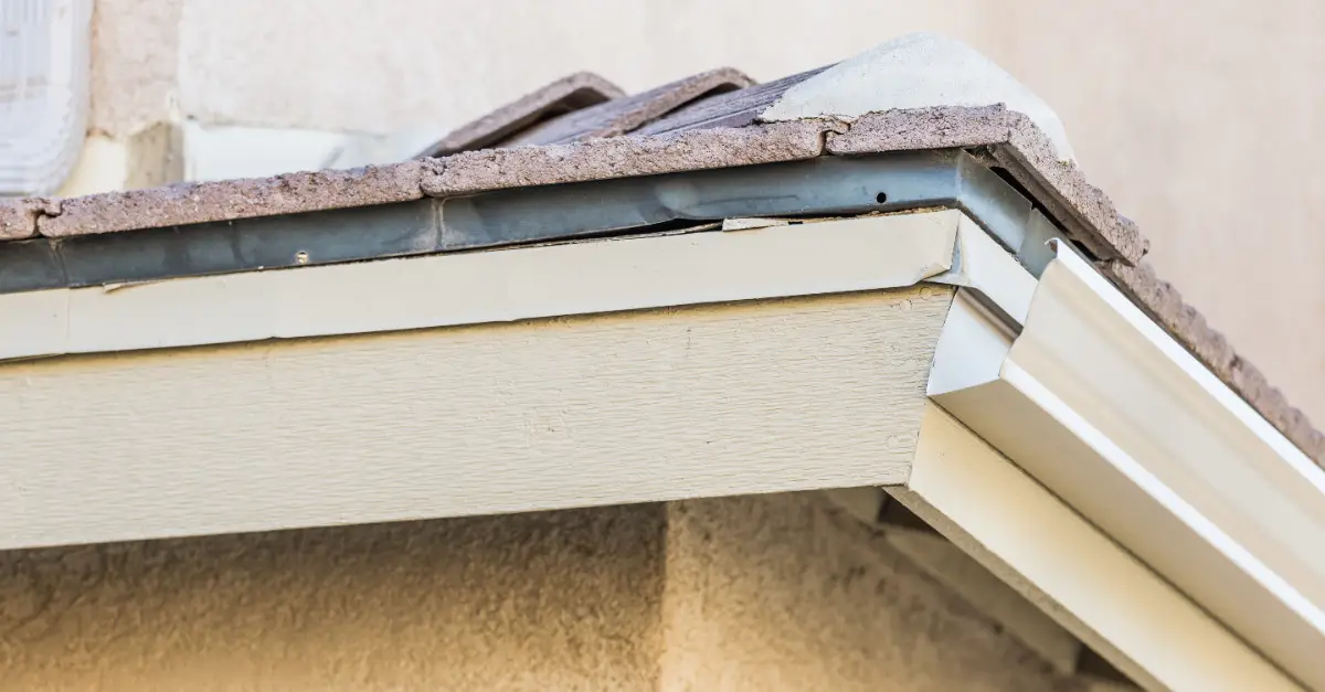 A close up of the corner of a residential roofline with exposed, visible fascia boards in an area where gutters have not been installed.