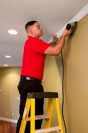  A McKinney finish carpenter from Mr. Handyman installing crown molding at the top of a wall.