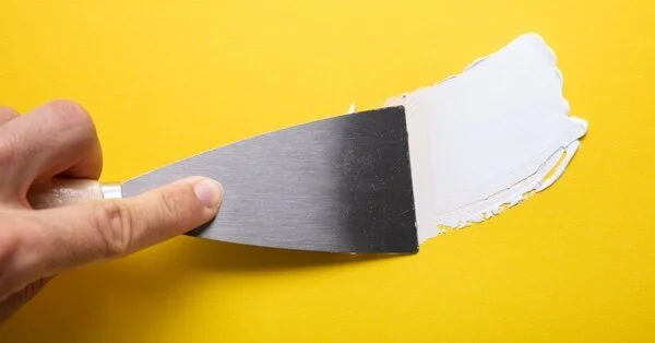 A handyman using tools to apply spackling during an appointment for drywall repair in North Oklahoma City.