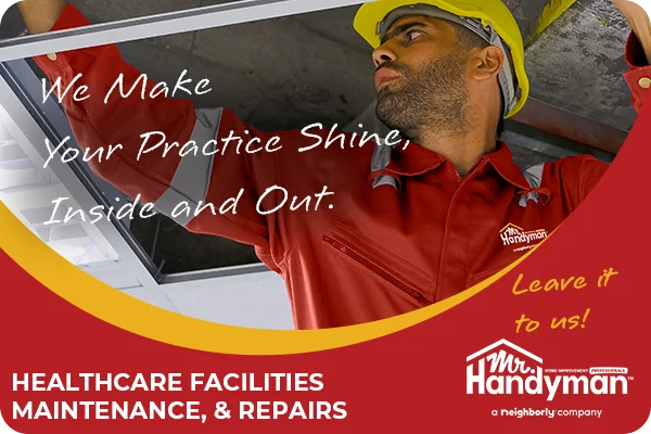 A skilled handyman in a red uniform carefully inspecting and repairing a ceiling at a medical office.