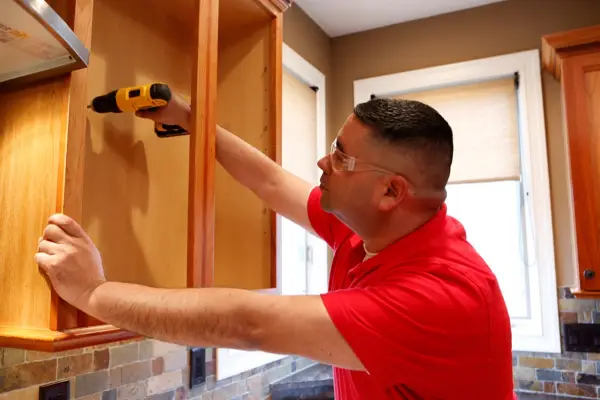 Mr. Handyman installing new cabinets during kitchen remodel in Keller home