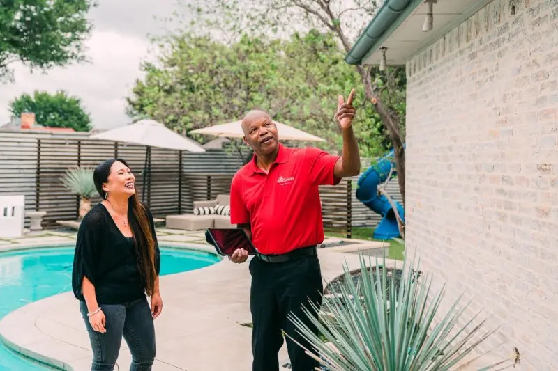 Mr. Handyman going over exterior pressure washing services with woman.