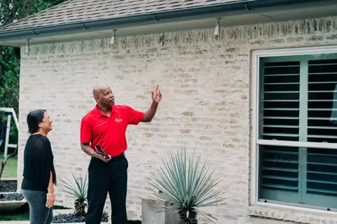 Mr. Handyman talking about gutter cleaning & repair with woman.