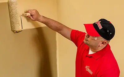 A My Handyman technician painting a wall using a paint roller.