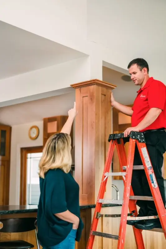 Mr. Handyman tech discussing crown molding & trim painting with woman.