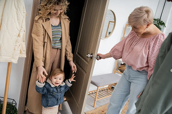 Grandmother opening a door for daughter and grandson.