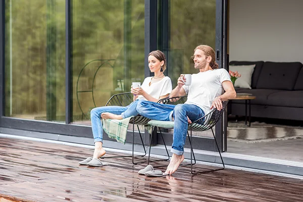 Couple relaxing on their patio, with a sleek sliding glass door installed in the background .