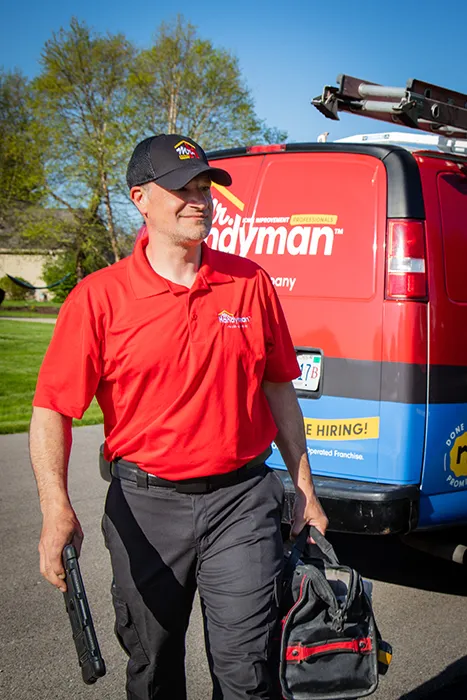 Mr. Handyman tech walking from work van to customer's home for a bathroom fan repair appointment 