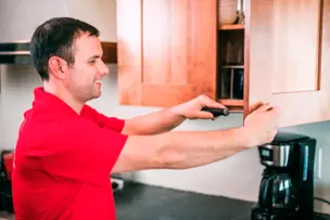 Handyman repairing a cabinet door handle at a home in Spokane.