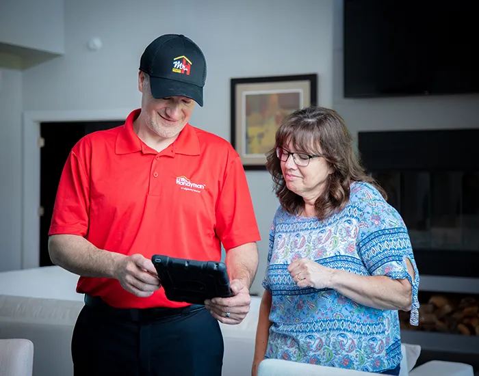 Mr. Handyman tech reviewing job details with a customer after completing a TV wall mount installation.