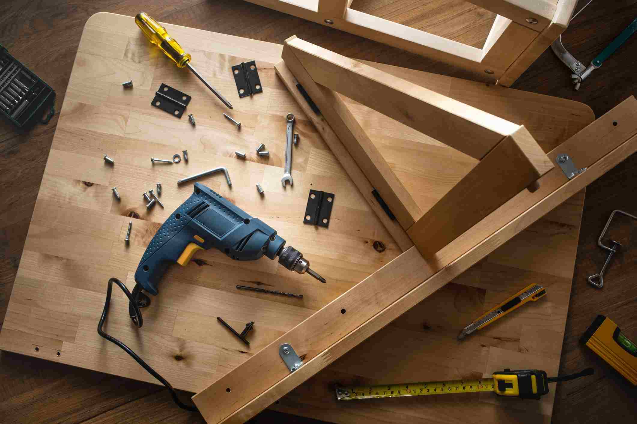 A drill and screws on a wood surface.