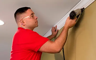 A My Handyman technician installing crown molding using a staple gun.