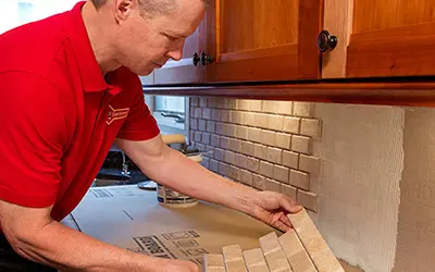 A My Handyman technician adding tile to a kitchen backsplash.